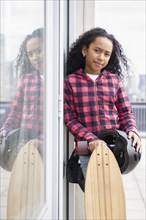 Mixed race girl standing with skateboard outdoors