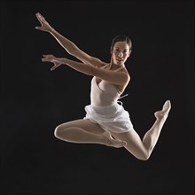 Hispanic ballet dancer leaping in mid-air
