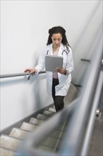High angle view of mixed race doctor reading medical chart on staircase
