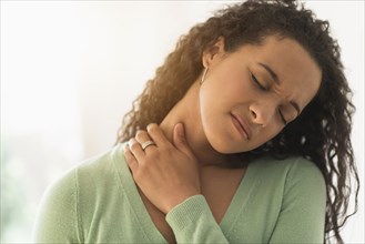 Close up of mixed race woman rubbing sore neck