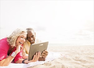 Older couple using digital tablet on beach