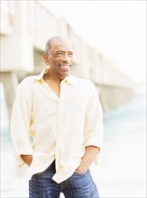 Older mixed race man smiling under boardwalk on beach