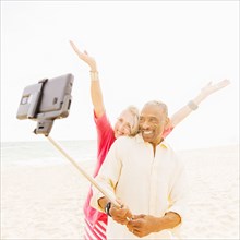 Older couple taking cell phone photograph on beach