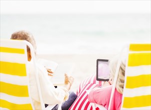 Older couple relaxing in lawn chairs on beach