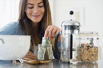 Caucasian woman putting money in jar