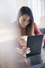 Caucasian woman using digital tablet with coffee