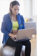 Caucasian woman using laptop in gym