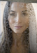 Caucasian woman peering through wet window