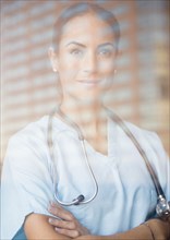 Caucasian doctor standing with arms crossed at window