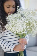 Mixed race girl holding bouquet of flowers