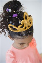 Mixed race girl wearing tiara and confetti
