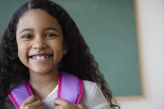 Smiling mixed race student wearing backpack in classroom