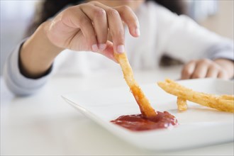 Close up of mixed race girl eating french fries