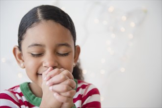 Close up of mixed race girl praying at Christmas