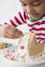 Mixed race girl decorating gingerbread house