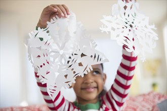 Mixed race girl holding paper snowflakes