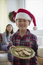 Asian boy holding plate of cookies for Santa