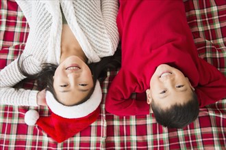 Asian brother and sister laying on blanket at Christmas
