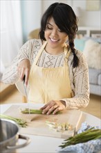 Pacific Islander woman slicing vegetables in kitchen