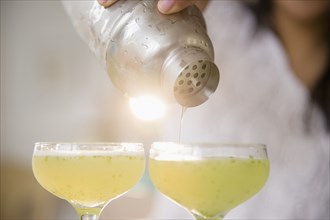 Pacific Islander woman pouring cocktails from shaker