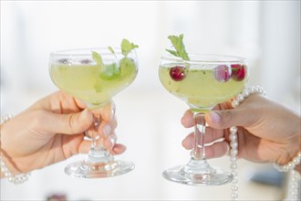 Women toasting with cocktails and pearl necklaces