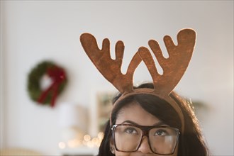 Pacific Islander woman wearing Christmas reindeer horns