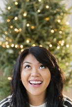 Pacific Islander woman looking up near Christmas tree