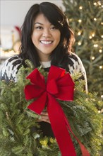 Pacific Islander woman holding Christmas wreath