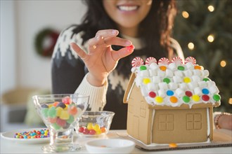 Pacific Islander woman decorating gingerbread house
