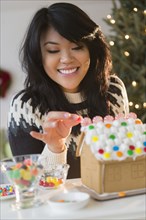 Pacific Islander woman decorating gingerbread house