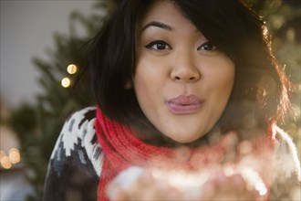 Pacific Islander woman blowing snow at Christmas