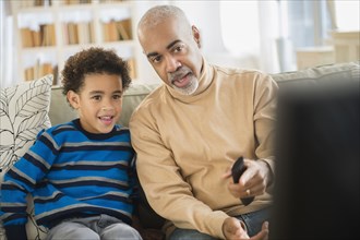 Mixed race grandfather and grandson watching television