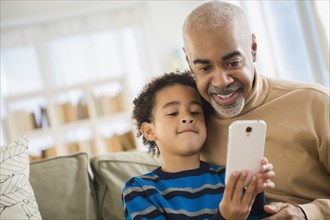 Mixed race grandfather and grandson using cell phone