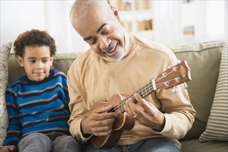Mixed race grandfather and grandson playing ukulele