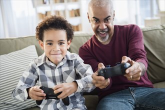 Mixed race grandfather and grandson playing video games