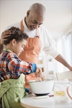 Mixed race grandfather and grandson baking in kitchen