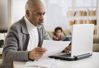 Mixed race man paying bills on laptop