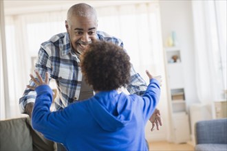 Mixed race grandfather and grandson greeting in living room