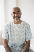 Mixed race older man sitting on hospital bed