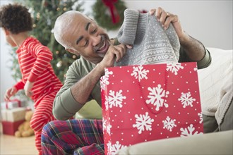 Mixed race grandfather and grandson opening Christmas gifts