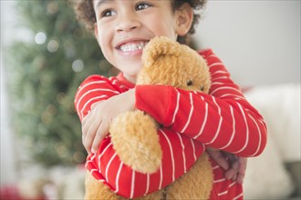 Mixed race boy hugging teddy bear at Christmas