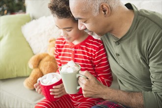 Mixed race grandfather and grandson drinking hot chocolate at Christmas