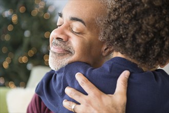 Mixed race grandfather and grandson hugging at Christmas