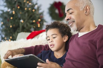 Mixed race grandfather and grandson using digital tablet at Christmas