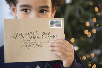 Mixed race boy holding letter to Santa for Christmas