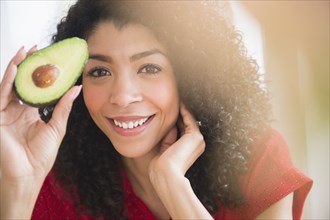 Mixed race woman holding avocado half