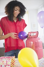 Mixed race woman inflating helium balloons for party