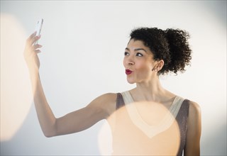 Mixed race woman taking cell phone selfie in evening gown