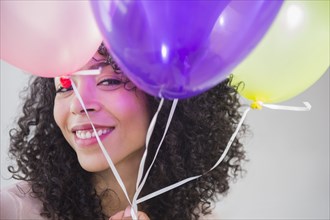 Mixed race woman holding bunch of balloons