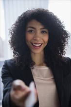 Mixed race businesswoman offering business card in office